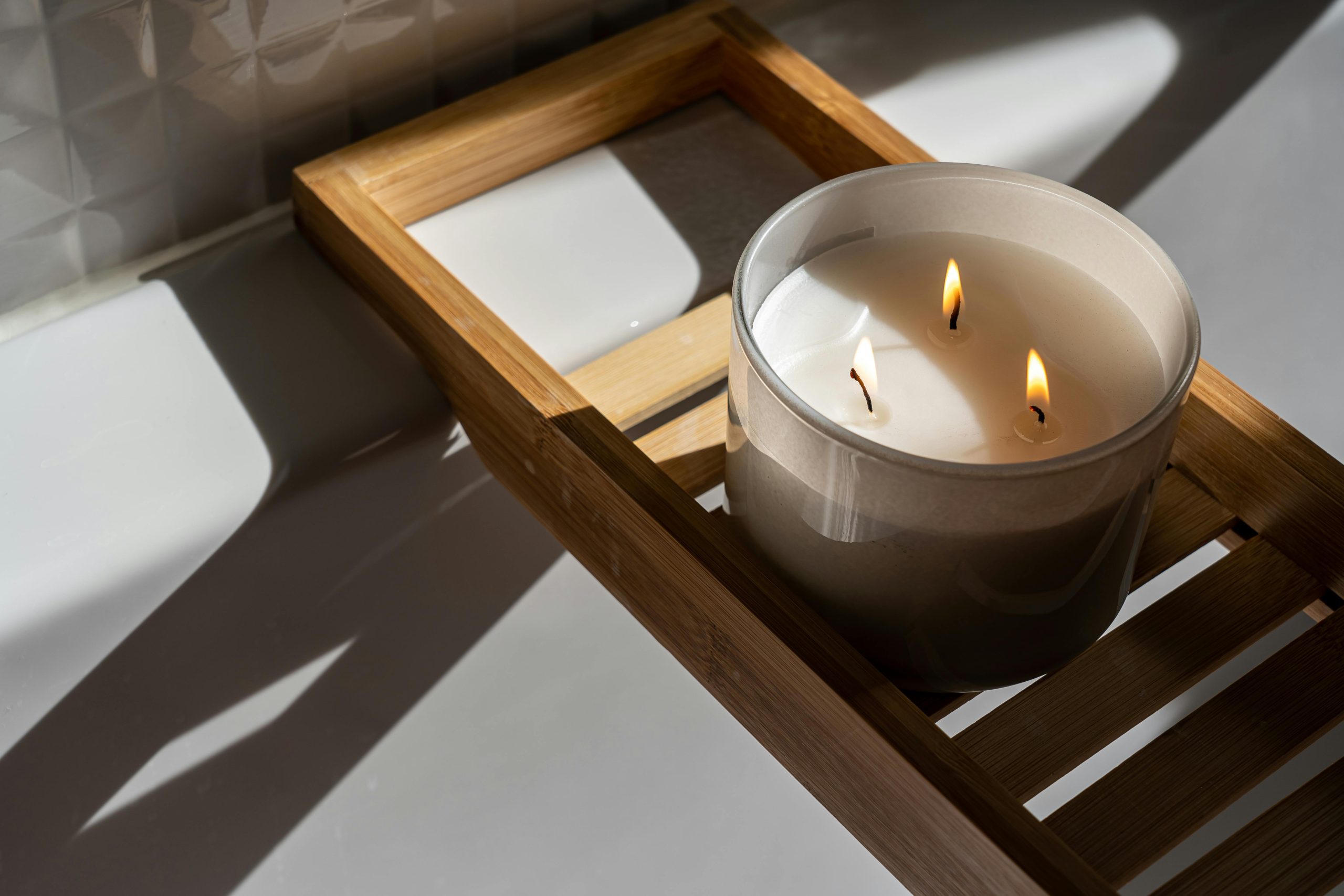 A minimalist setting with a lit candle on a wooden tray, casting warm shadows and creating a soothing ambiance.